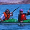 Dois praticantes de caiaque remando lado a lado no Lago Potrerillos usando coletes salva-vidas.