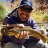 Pescador com mosca segurando uma truta marrom capturada em Mendoza – Pesca com mosca nos Andes.