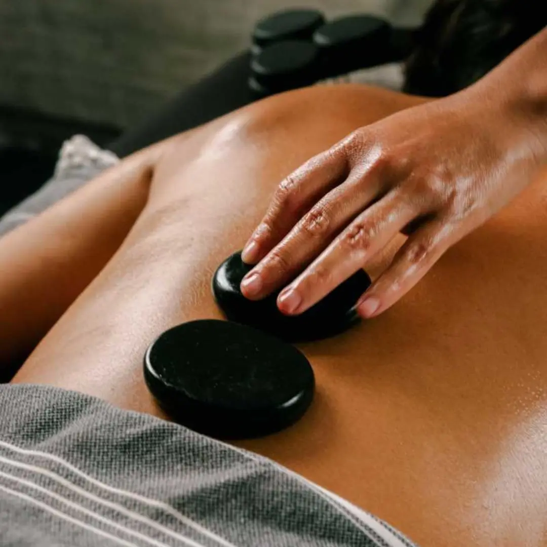 Therapist applying hot stones to client's back during a spa massage
