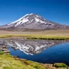Vista clara do vulcão Maipo refletida nas águas calmas da Laguna del Diamante.