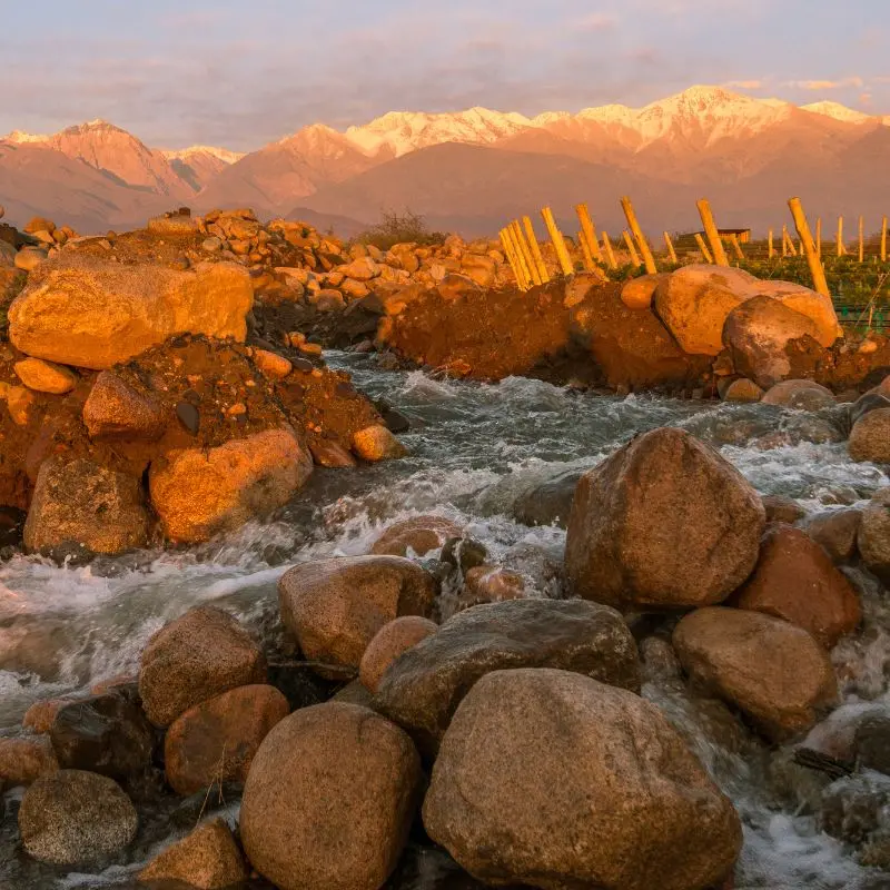Rio de montanha e paisagens rochosas ao pôr do sol nos Andes.