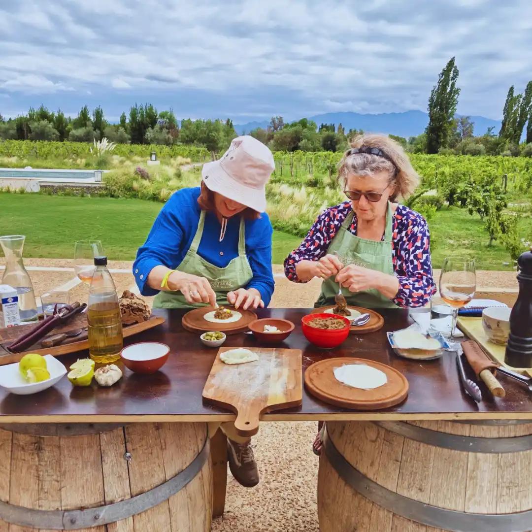 Guests making traditional Argentine empanadas outdoors at a winery in Mendoza.
